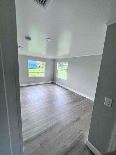 unfurnished room with visible vents, baseboards, and wood finished floors