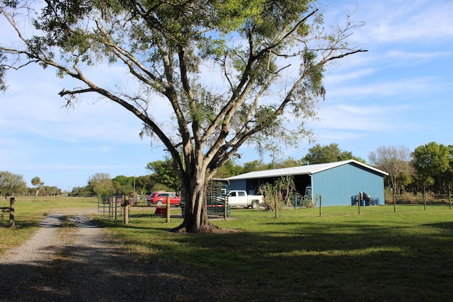 view of yard featuring fence, a pole building, a carport, and an outdoor structure