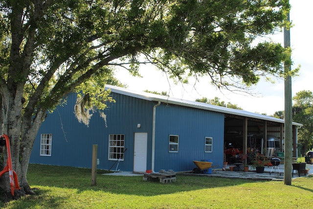 back of house with an outbuilding, a yard, and a patio