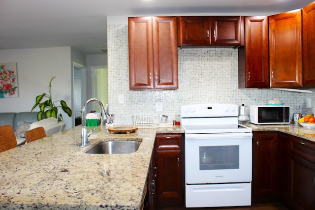 kitchen with light stone counters, a peninsula, a sink, white range with electric stovetop, and decorative backsplash