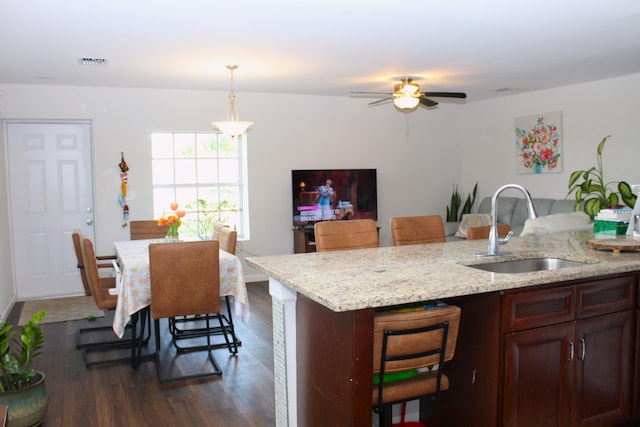 kitchen with visible vents, light stone counters, open floor plan, dark wood-type flooring, and a sink