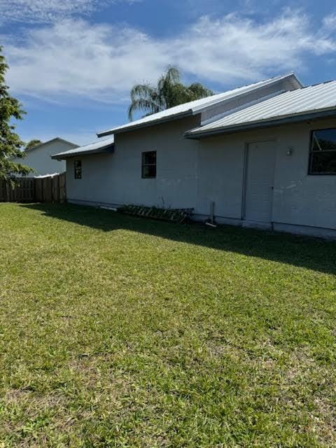 view of home's exterior featuring metal roof, a lawn, and fence