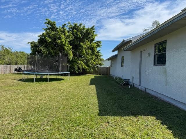 view of yard featuring a trampoline and fence