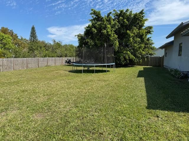 view of yard featuring a trampoline and a fenced backyard