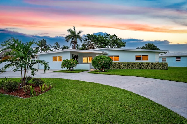 view of front facade featuring concrete driveway, a yard, and stucco siding