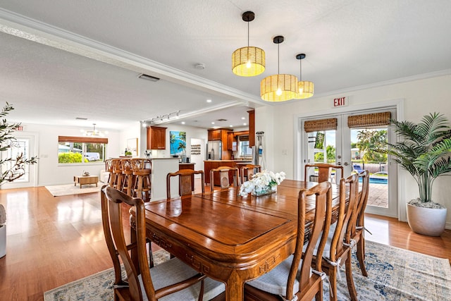 dining space featuring french doors, visible vents, a textured ceiling, and light wood finished floors