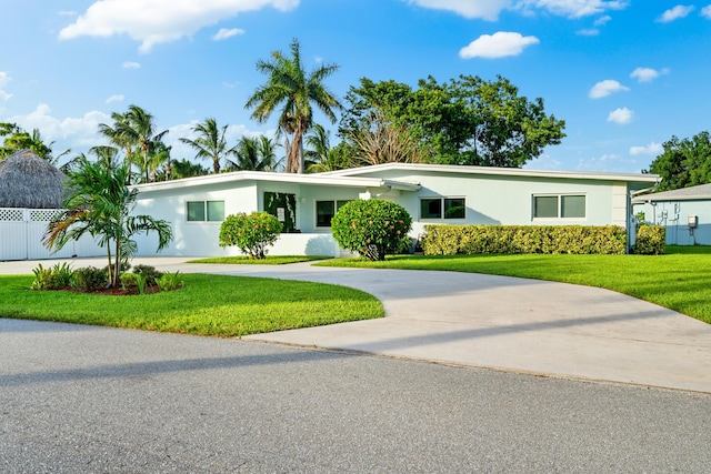 view of front facade featuring a front yard, curved driveway, fence, and stucco siding