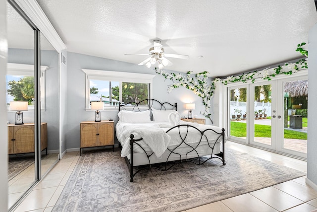 bedroom with light tile patterned floors, access to outside, multiple windows, and a textured ceiling