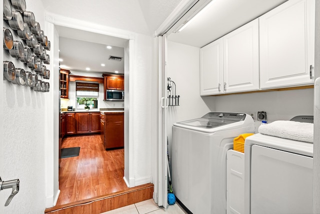 clothes washing area with recessed lighting, visible vents, light wood-style floors, cabinet space, and washing machine and clothes dryer