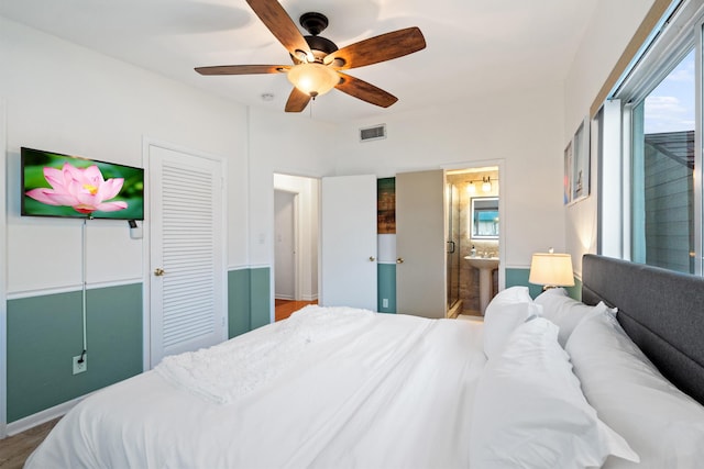 bedroom featuring ensuite bath, visible vents, and a ceiling fan