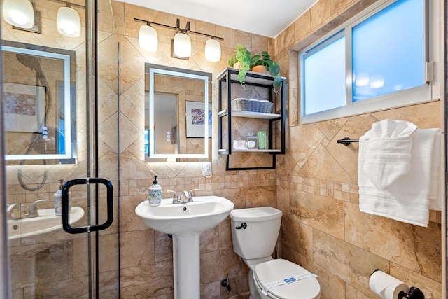 full bathroom featuring a stall shower, a sink, tile walls, and toilet