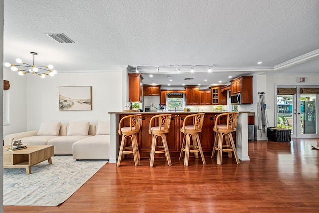 interior space featuring appliances with stainless steel finishes, visible vents, glass insert cabinets, and dark wood-type flooring