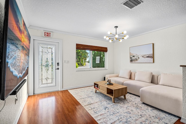 living area featuring visible vents, crown molding, an inviting chandelier, and wood finished floors