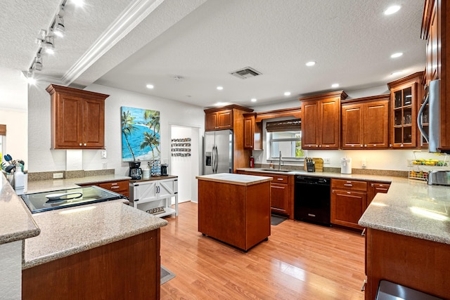 kitchen with a textured ceiling, a sink, visible vents, appliances with stainless steel finishes, and light wood-type flooring