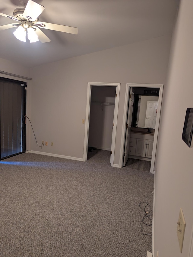 unfurnished bedroom featuring baseboards, connected bathroom, a spacious closet, carpet flooring, and vaulted ceiling
