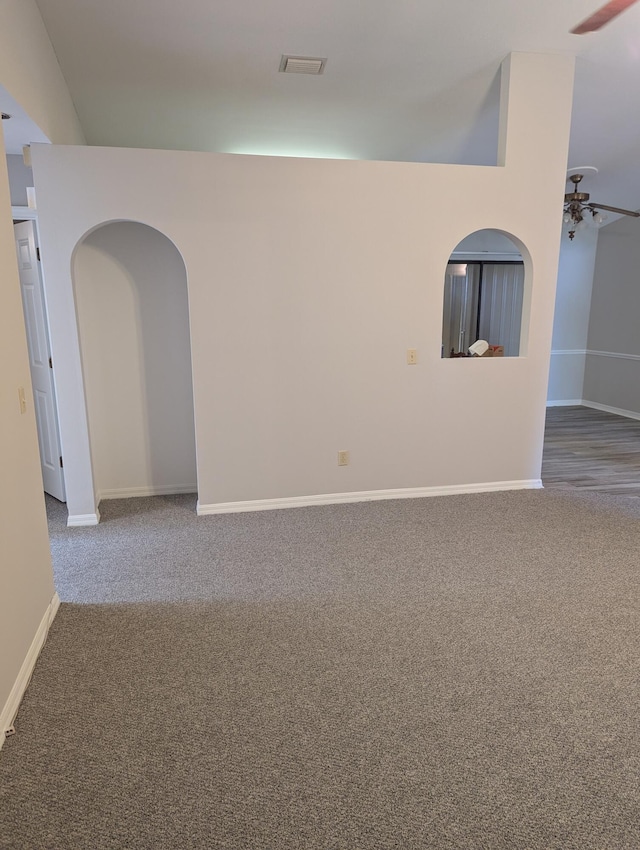 empty room featuring baseboards, arched walkways, carpet, and ceiling fan