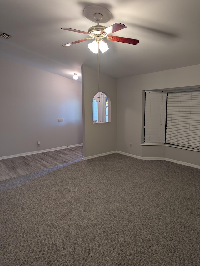 empty room with carpet flooring, ceiling fan, visible vents, and baseboards