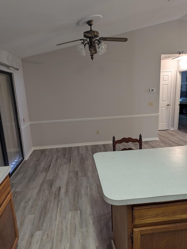 dining space with light wood-style floors, baseboards, ceiling fan, and lofted ceiling