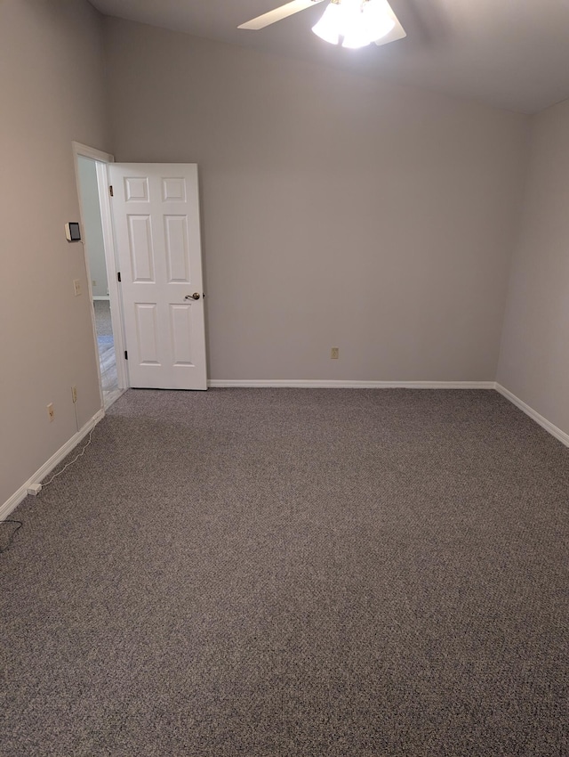 unfurnished room featuring dark colored carpet, a ceiling fan, and baseboards