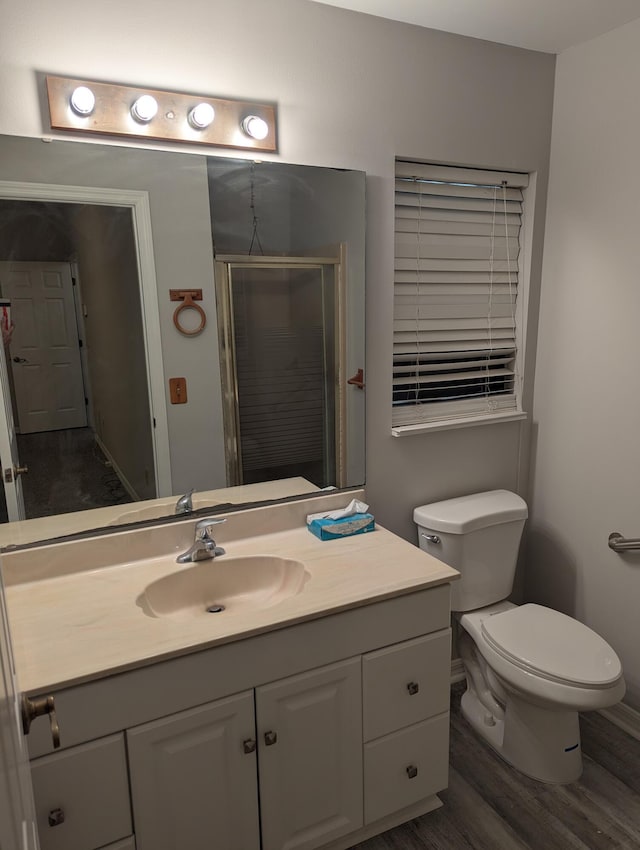 bathroom with toilet, a stall shower, wood finished floors, and vanity