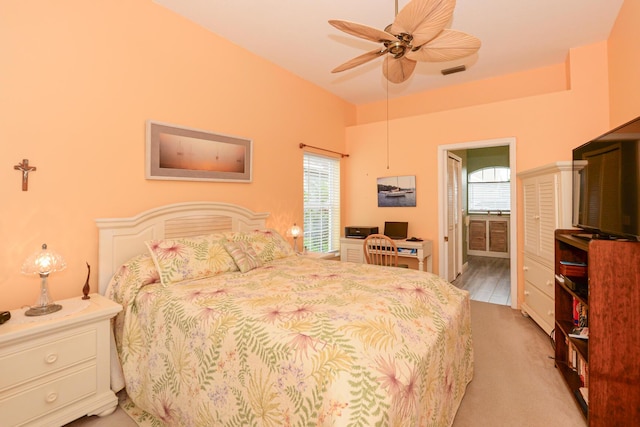 bedroom with light carpet, visible vents, ensuite bathroom, and a ceiling fan