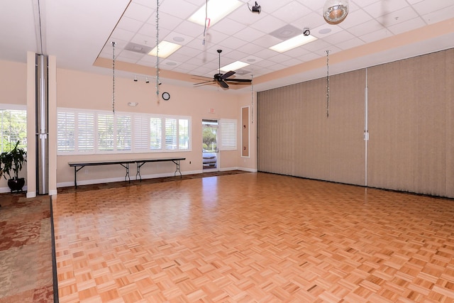 unfurnished room with a paneled ceiling, baseboards, a high ceiling, and a ceiling fan