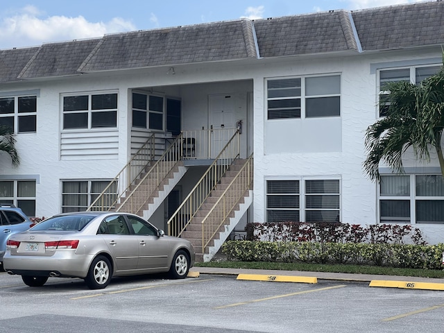 exterior space with roof with shingles, mansard roof, and stucco siding