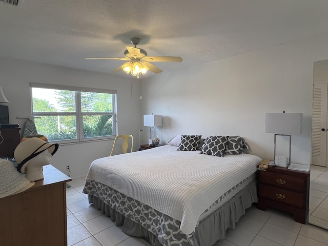 bedroom with light tile patterned floors, visible vents, a ceiling fan, and a textured ceiling