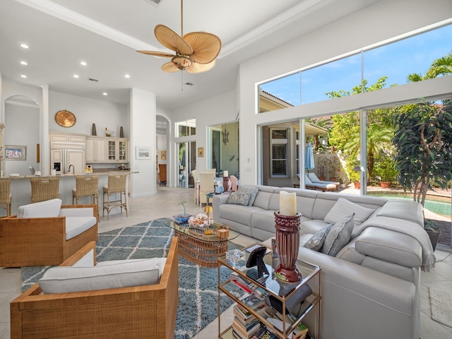 living room with light tile patterned floors, recessed lighting, a ceiling fan, and a towering ceiling