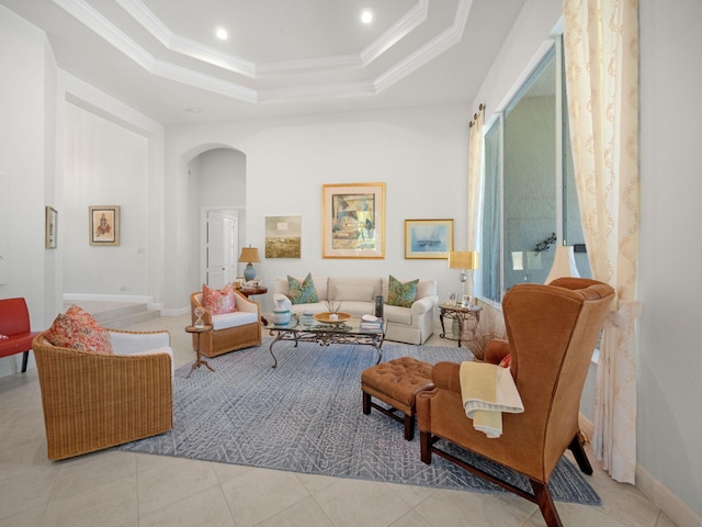 living room featuring tile patterned floors, a tray ceiling, arched walkways, crown molding, and baseboards