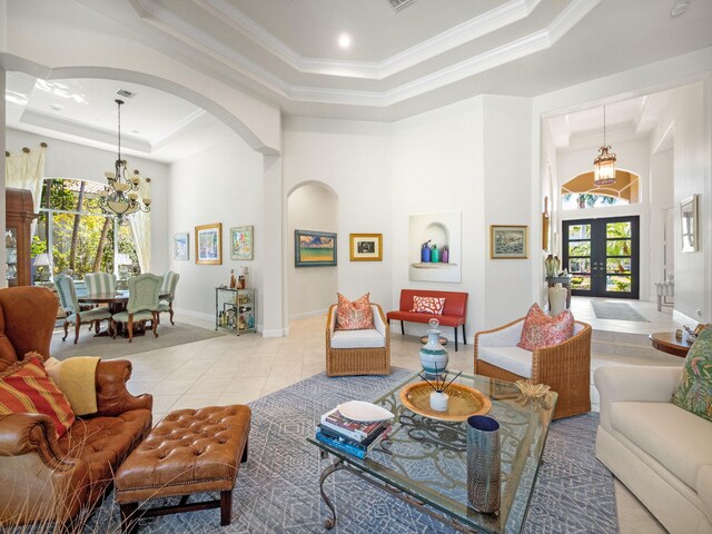 living area featuring a raised ceiling, light tile patterned flooring, french doors, and a healthy amount of sunlight