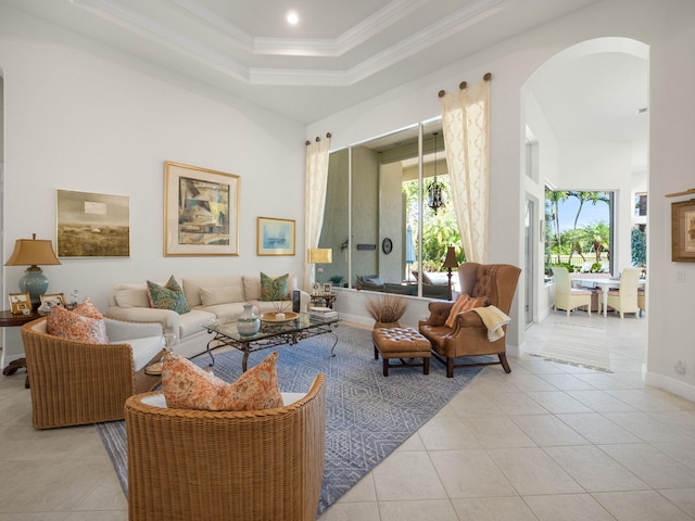 living area featuring arched walkways, crown molding, light tile patterned floors, a raised ceiling, and a towering ceiling