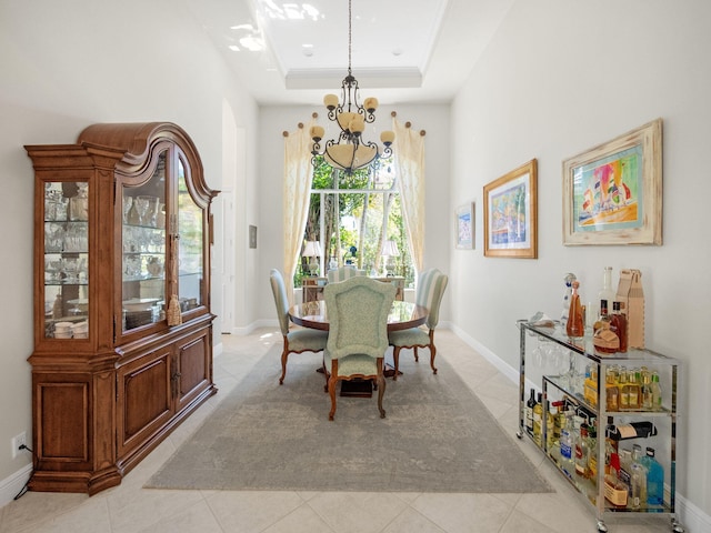 dining area featuring a notable chandelier, a tray ceiling, crown molding, light tile patterned floors, and baseboards