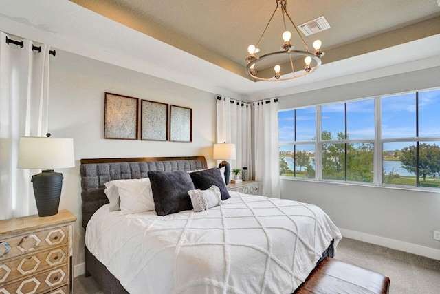 bedroom featuring visible vents, a notable chandelier, a tray ceiling, carpet floors, and baseboards