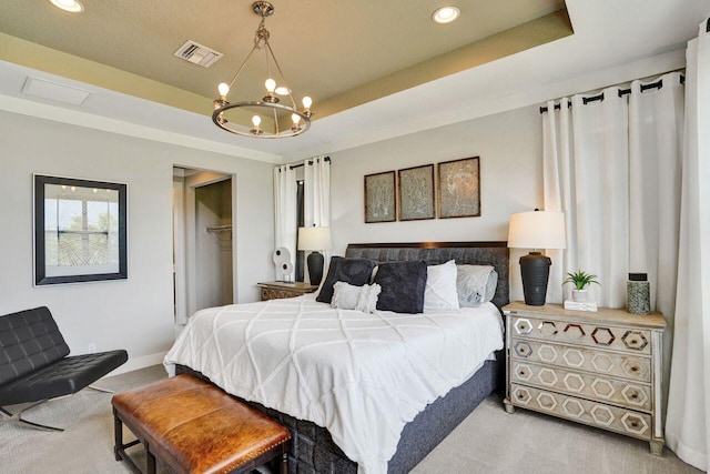 carpeted bedroom featuring an inviting chandelier, a tray ceiling, visible vents, and a closet