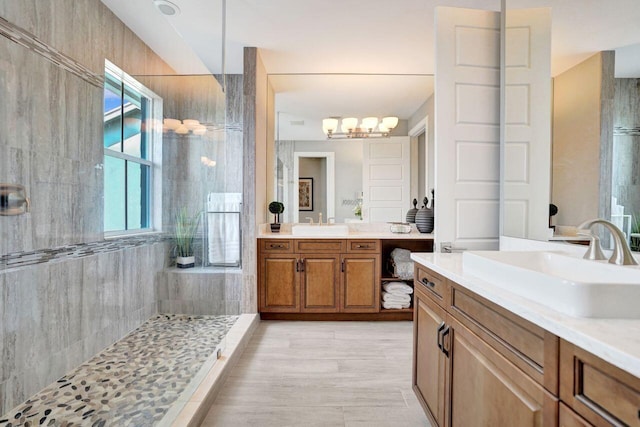 bathroom with two vanities, a tile shower, and a sink