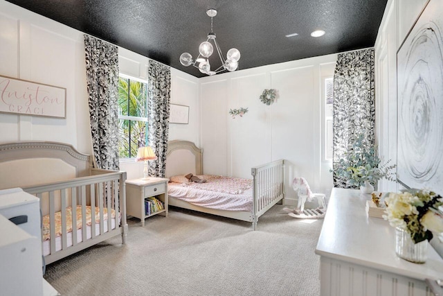 bedroom featuring a notable chandelier, carpet, a decorative wall, and a textured ceiling