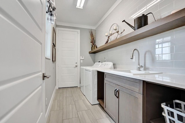 laundry area featuring cabinet space, washing machine and dryer, baseboards, and a sink