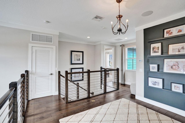 hallway with wood finished floors, an upstairs landing, and visible vents