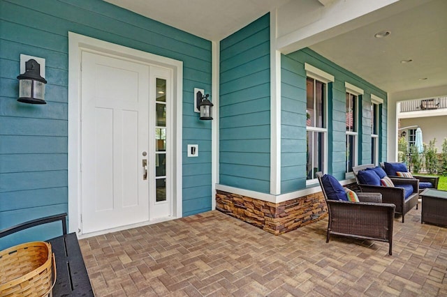 view of exterior entry with stone siding and a porch