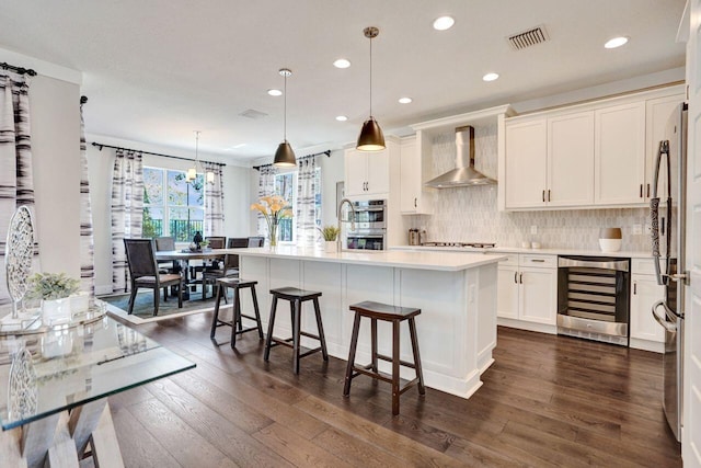 kitchen with visible vents, beverage cooler, light countertops, wall chimney exhaust hood, and dark wood-style flooring