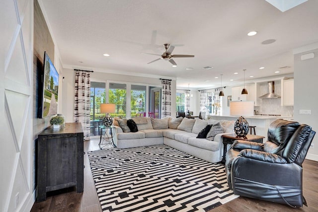 living area featuring recessed lighting, dark wood finished floors, and ceiling fan with notable chandelier