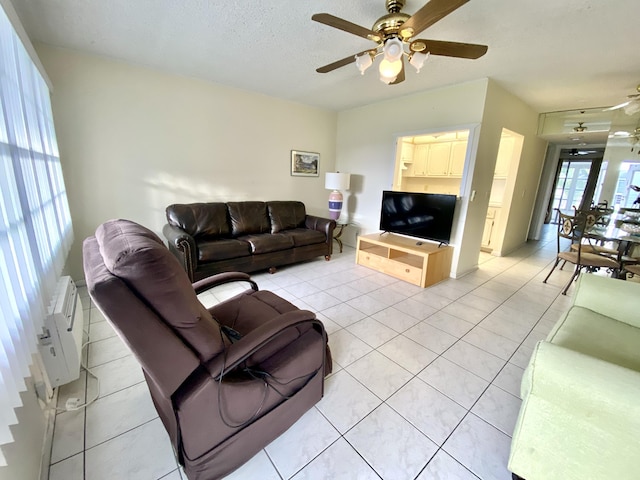 living room featuring light tile patterned floors, a textured ceiling, and a ceiling fan