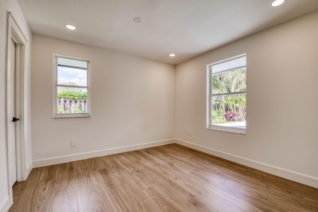 spare room with light wood-type flooring, plenty of natural light, and baseboards