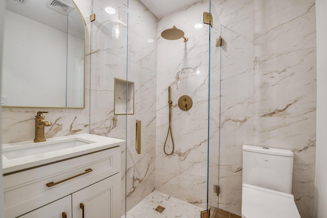 bathroom with toilet, visible vents, vanity, tile walls, and a marble finish shower