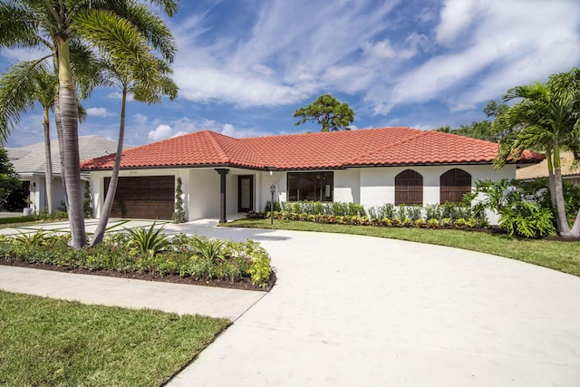 mediterranean / spanish-style home with a tiled roof, concrete driveway, an attached garage, and stucco siding