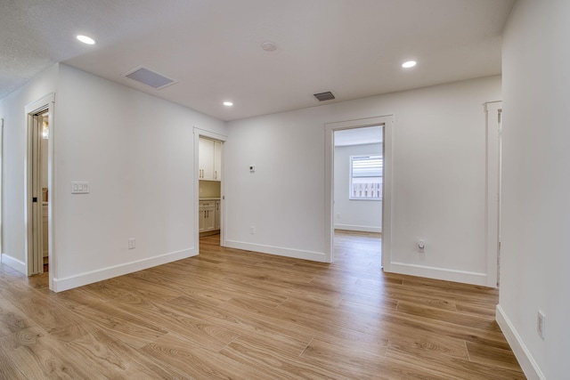 empty room featuring recessed lighting, visible vents, and light wood finished floors