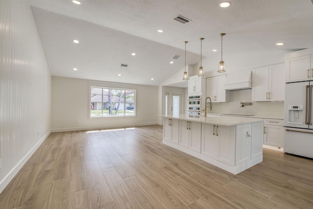 kitchen featuring light countertops, custom range hood, white cabinets, a sink, and white appliances