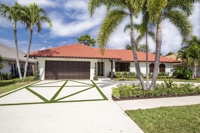 mediterranean / spanish-style house featuring an attached garage, stucco siding, concrete driveway, and a tiled roof