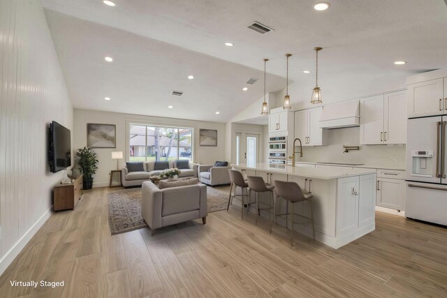 unfurnished living room featuring light wood-style flooring, visible vents, vaulted ceiling, and a sink